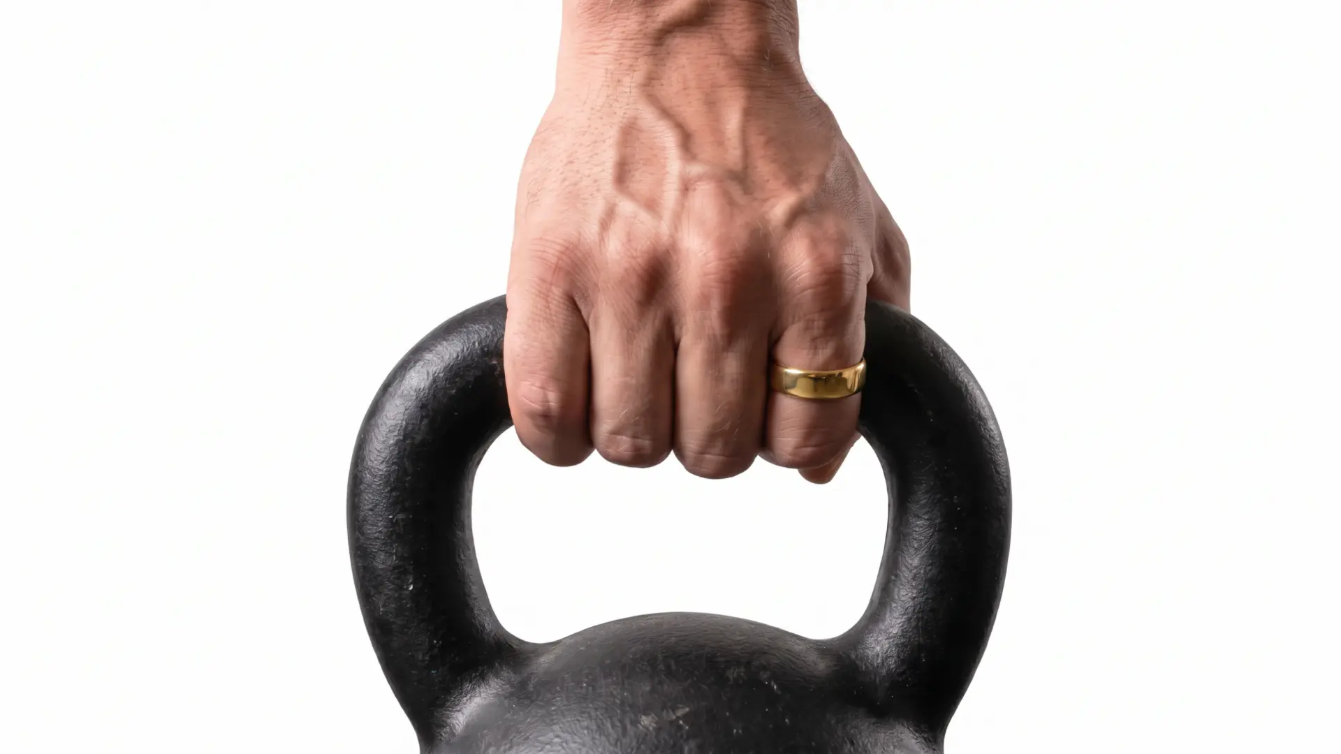 Hand wearing a gold ring while holding a black kettlebell