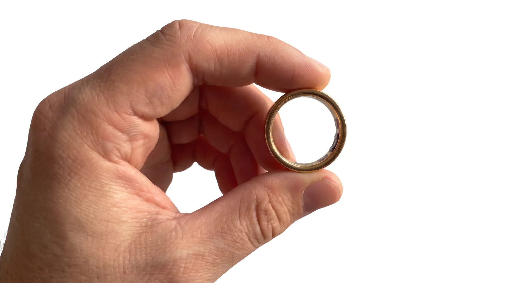 A hand holding the 18ct gold Nuet ring, its health sensors visible on the inside